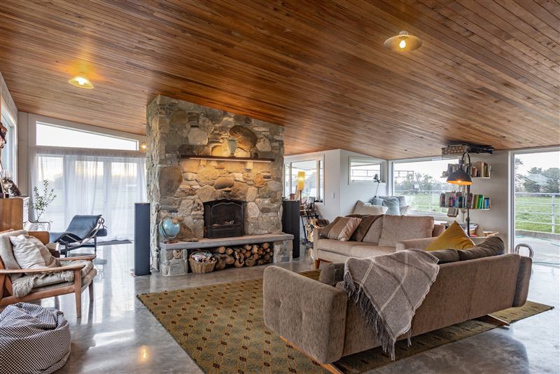 Living area with a stone fireplace and timber ceiling