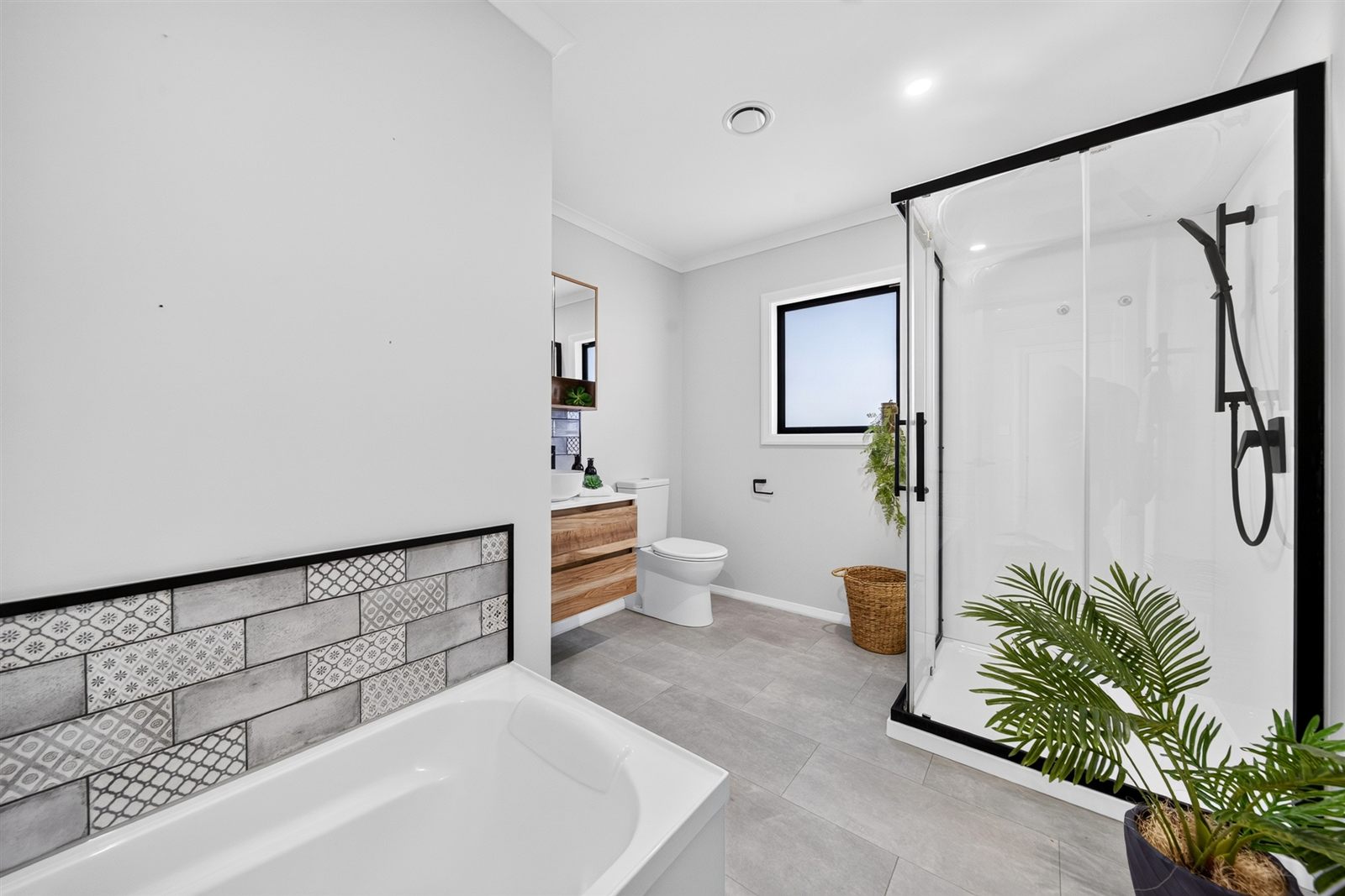 A renovated bathroom with a tiled bath, timber vanity and glass shower